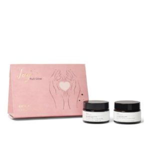 vaaleabpunainen lahjapakkaus kultaisilla yksityiskohdilla ja kaksi ruskeaa lasipurkkia vieressä valkoisilla etiketeillä